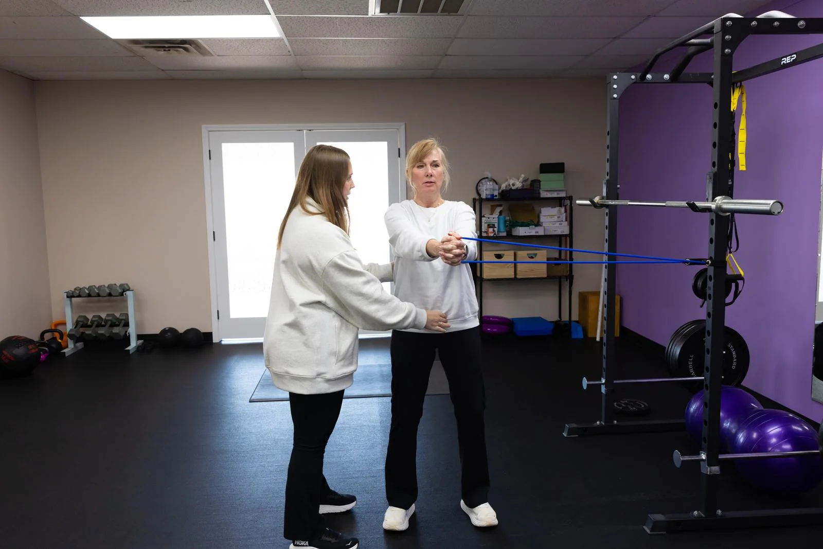 A Vitality pelvic health doctor of physical therapy guiding a patient through resistance band exercise in the Tulsa clinic gym