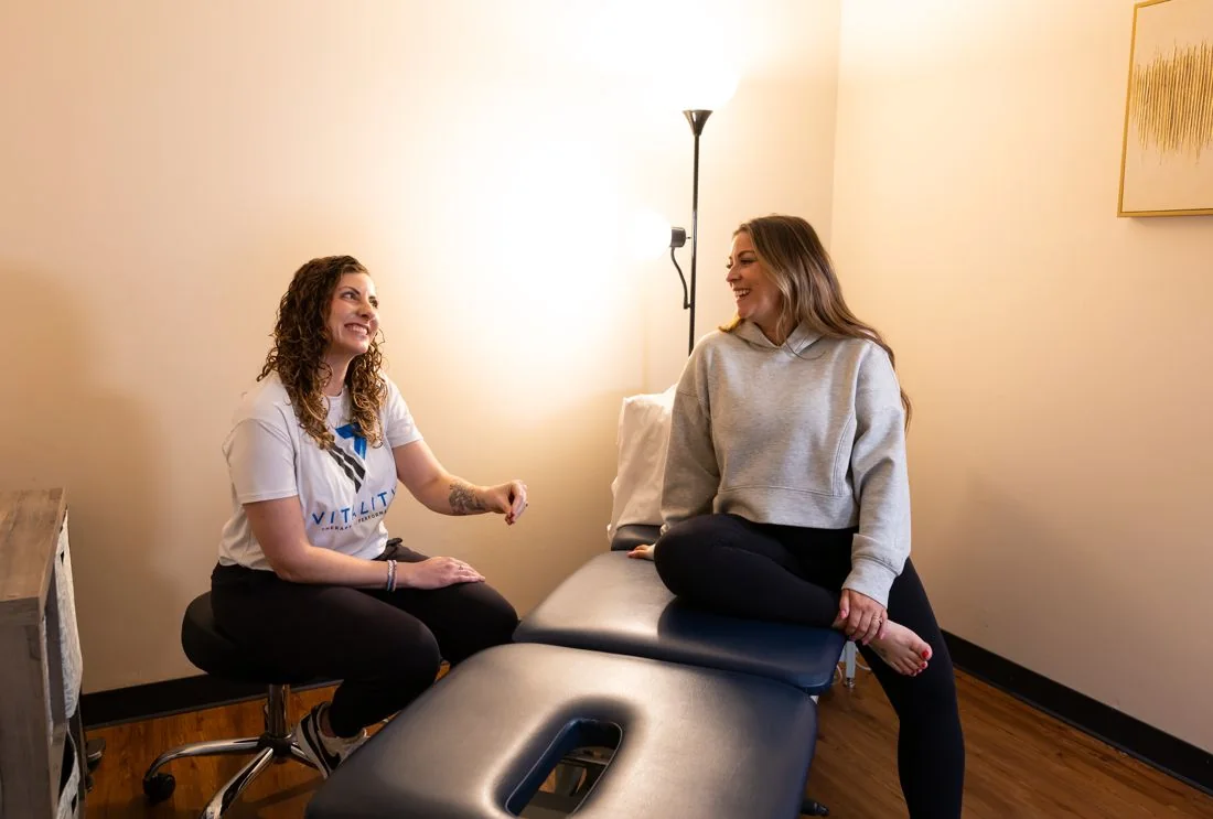 Therapist and patient talking beside the treatment table at Vitality Pelvic Health