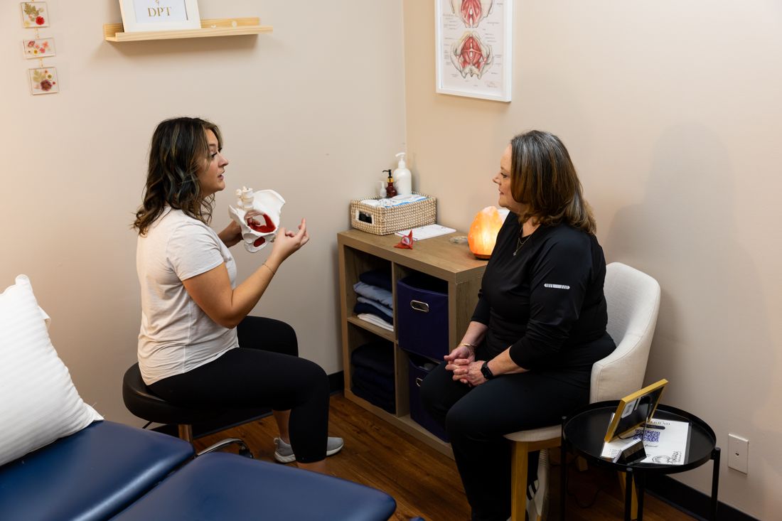 Pelvic floor physical therapist explaining a pelvic model to a patient in a consult room