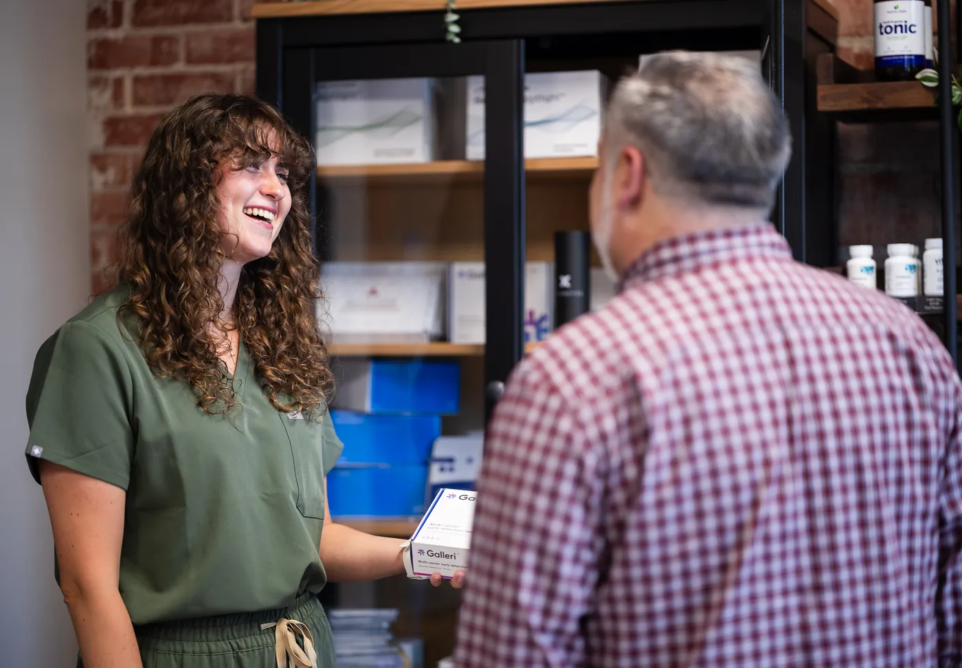 Melissa Bleakley, VFM medical assistant, handing a patient a lab kit at the supplement bar